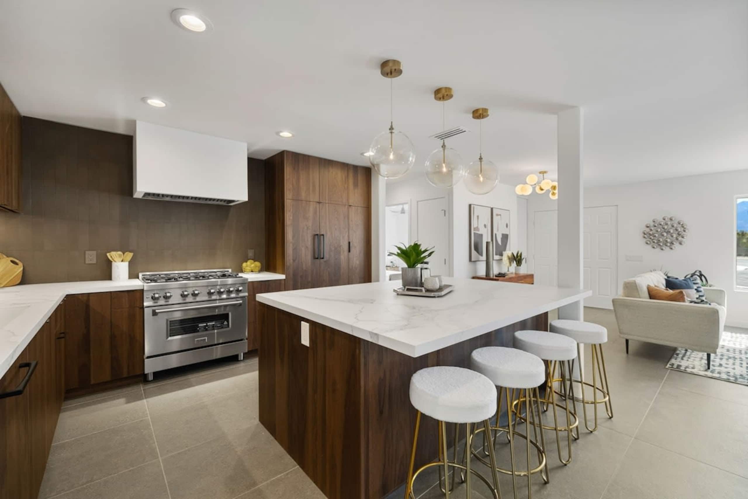 Walnut chef's kitchen with quartz waterfall island and brass pendants